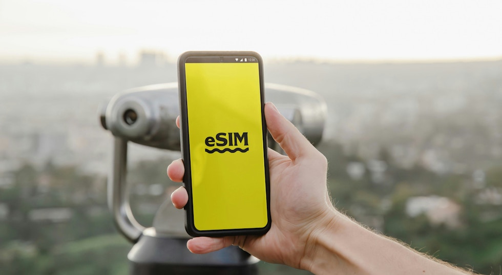 A hand holding a phone and on the screen it reads 'eSIM'.